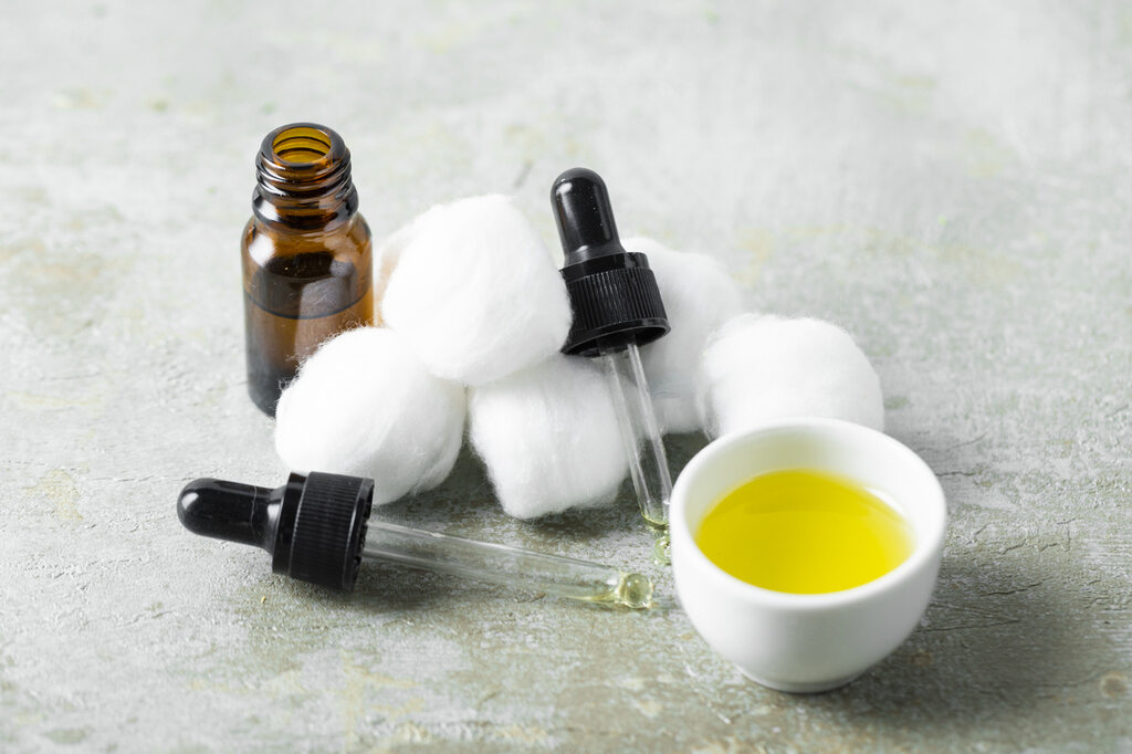 óleo de algodão com conta-gotas e bolas de algodão em aplicação cosmética natural