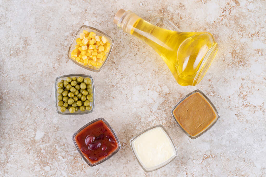 Ingredientes e molhos industrializados ao lado de óleo vegetal, produtos que podem conter gordura vegetal hidrogenada em sua composição.