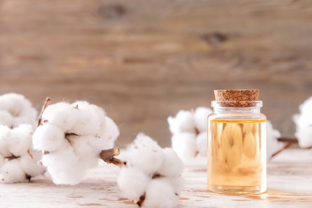 óleo vegetal de girassol em frascos de vidro com sementes e flores de girassol sobre mesa de madeira