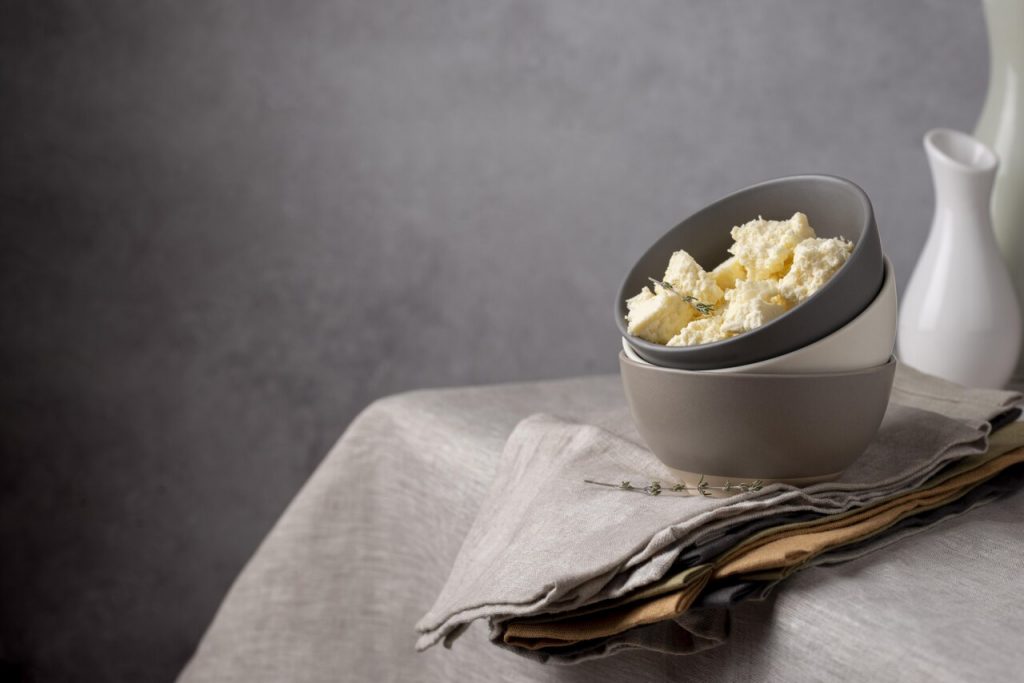 Margarina cremosa em tigela sobre mesa com tecido neutro em ambiente clean