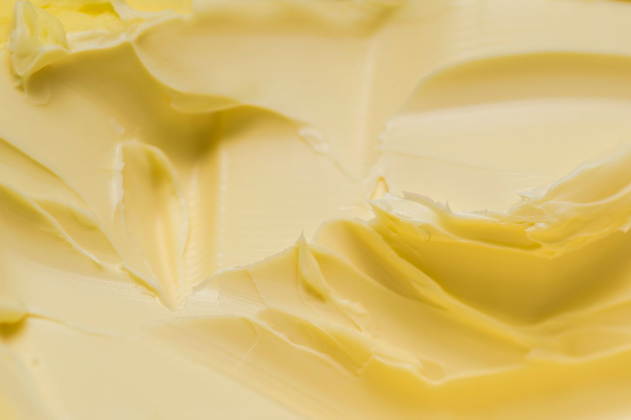 Close na textura da margarina espalhada, evidenciando cremosidade e aspecto uniforme do produto