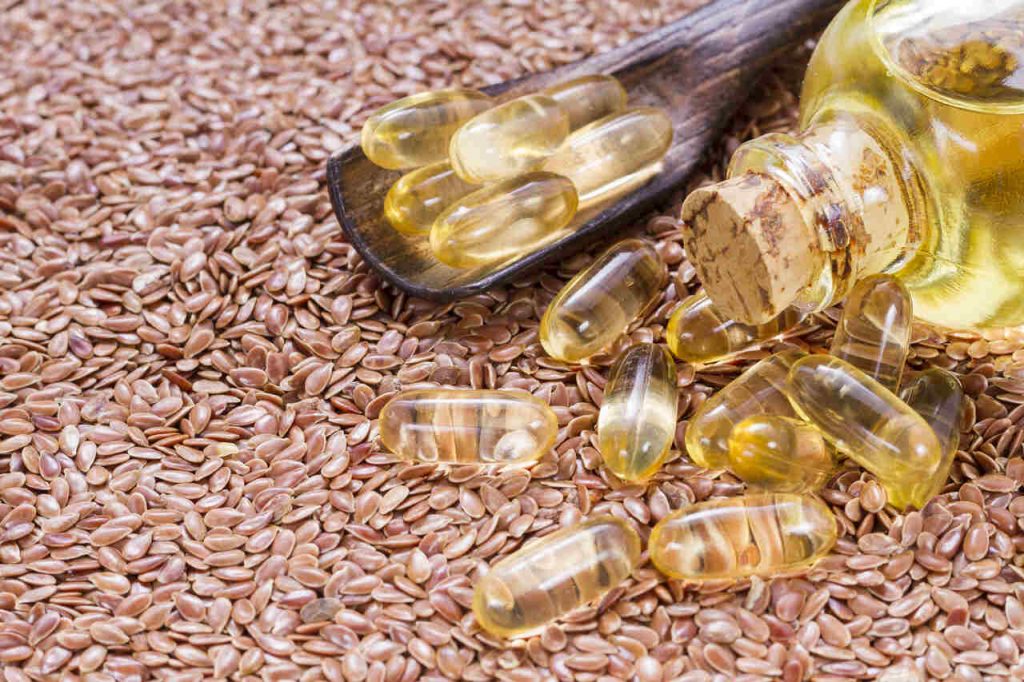 cápsulas de óleo vegetal sobre sementes com frasco ao lado representando óleos para consumo