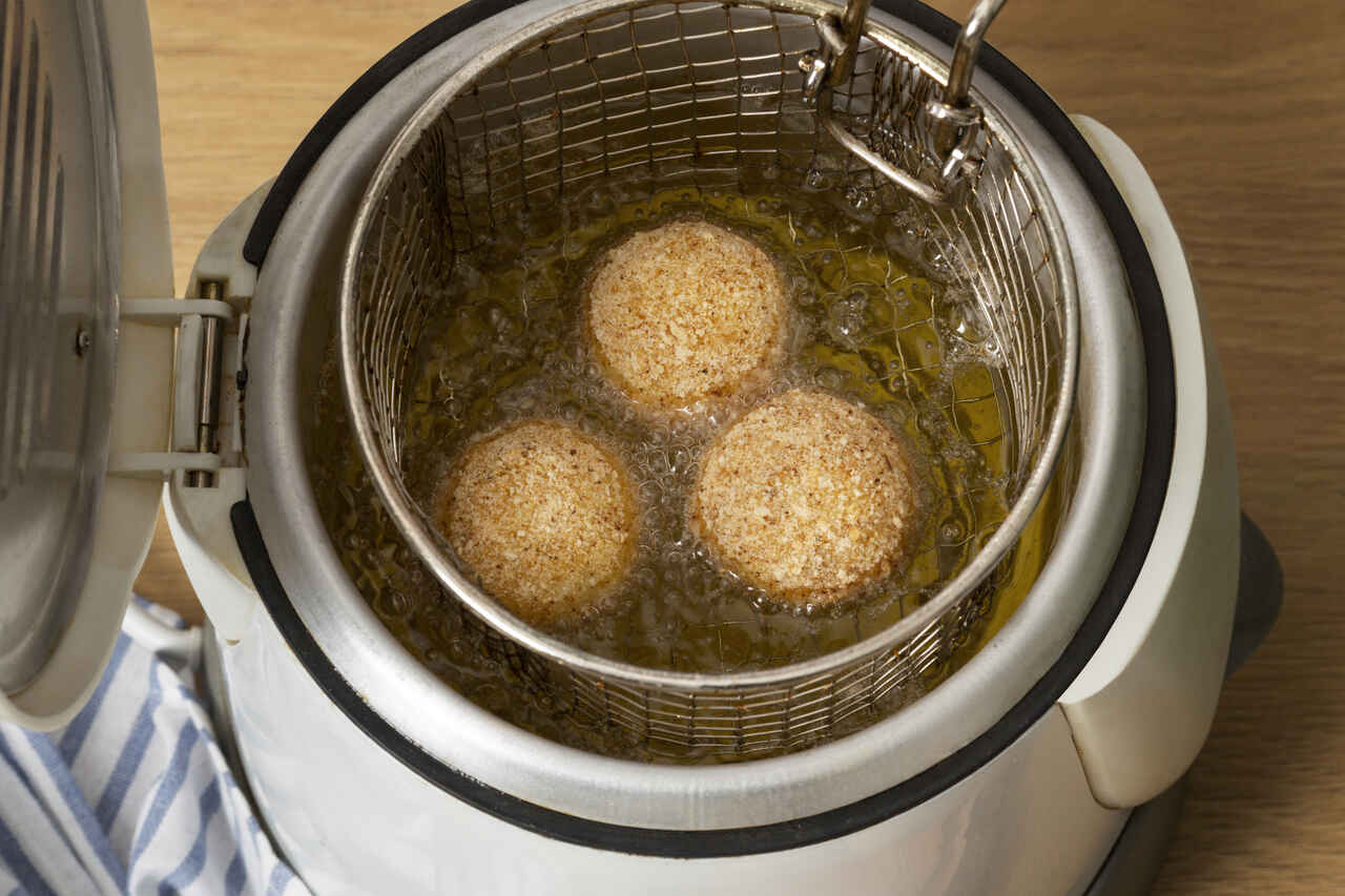 Alimentos sendo fritos por imersão em óleo quente dentro de fritadeira elétrica