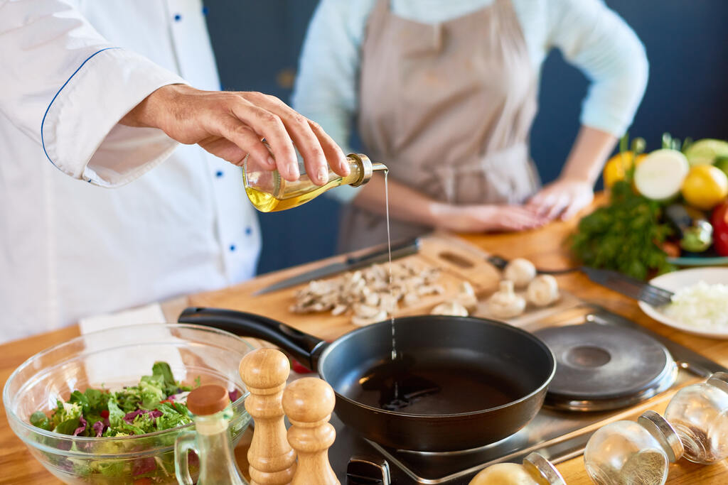 chef adicionando óleo de algodão em frigideira para preparo de alimentos na cozinha