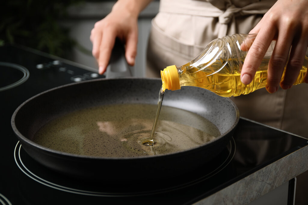 óleo de cozinha sendo despejado em frigideira quente no fogão para preparo de alimentos
